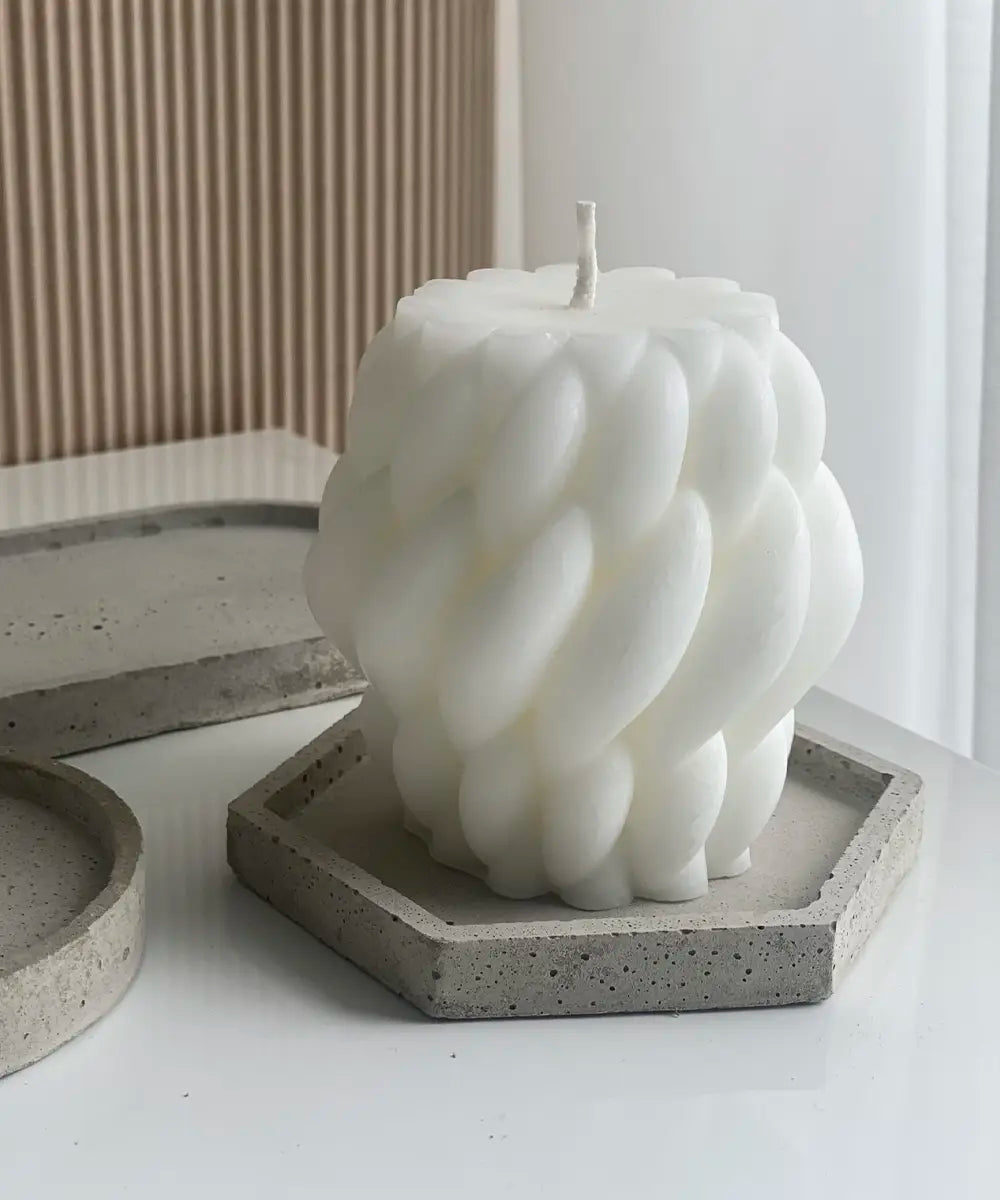 ett vackert stearinljus i en skulpterad form på ett betongfat