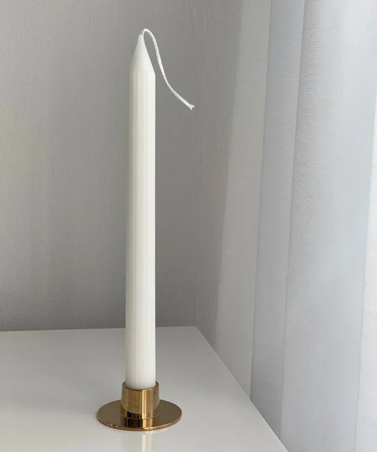 ett vackert kronljus i vit färg som stor i ett lågt ljusfat av mässing på ett vitt bord
